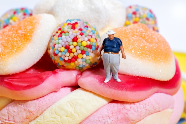 Fat boy miniature figure standing amongst candies