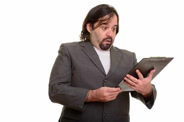 Fat Caucasian businessman looking shocked while reading on clipboard