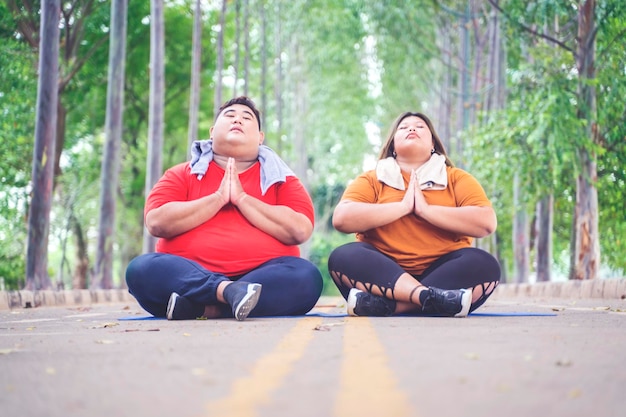 Fat couple meditating while sitting on the road