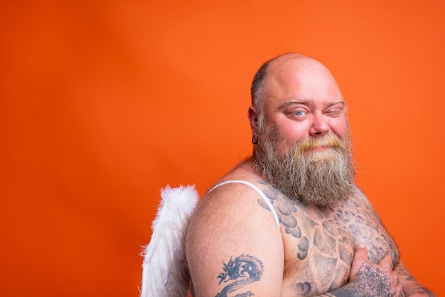 Fat doubter man with beard tattoos and wings acts like an angel