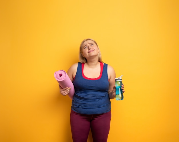 Ragazza grassa fa ginnastica a casa. espressione stanca