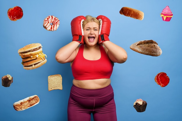 Fat girl is worried because she cannot lose weight and always think about eating. purple background