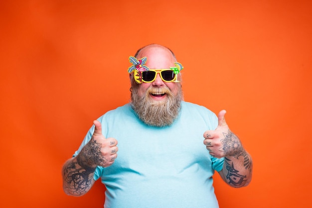 Fat happy man with beard tattoos and sunglasses is ready for the summer