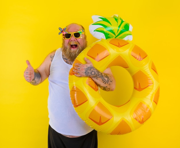 Fat happy man with wig in head is ready to swim with a donut lifesaver