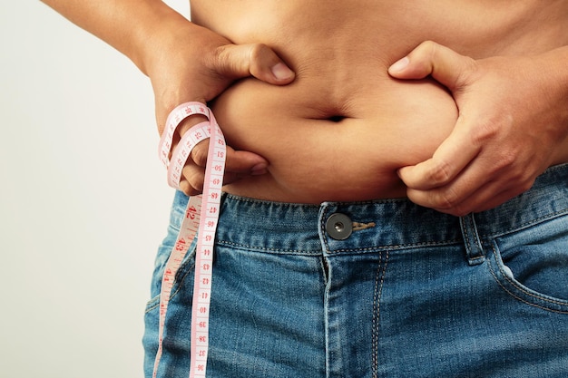 Толстяк проверяет тело с избыточным весом на животе с измерительной лентой в руке
