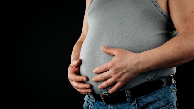 A fat man checking his weight on a black background