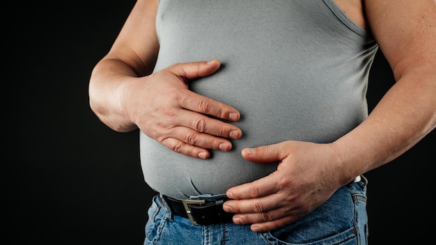 A fat man checking his weight on a black background