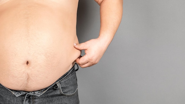 Fat man, checking his weight, on a gray background.