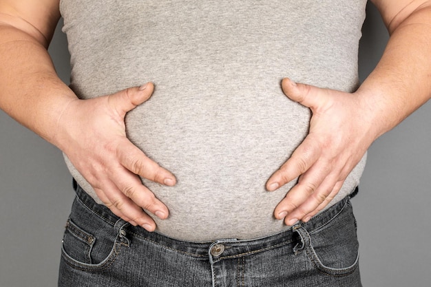 Fat man checking his weight on a gray background