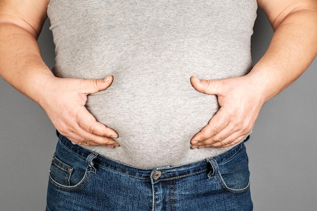 Fat man checking his weight on a gray background