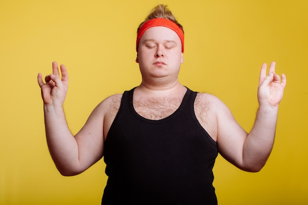 Fat man relaxing with meditation on yellow wall