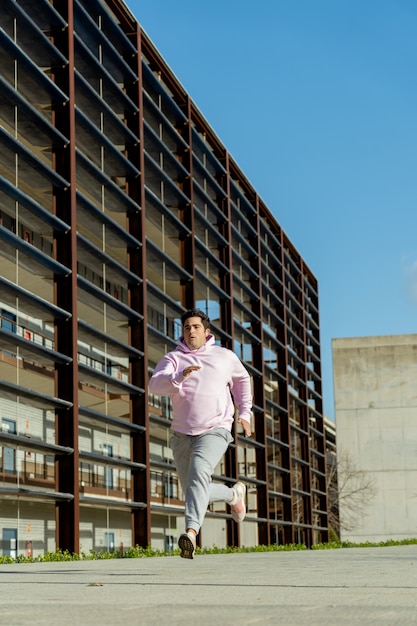 Fat man running through the city center at noon, wears sportswear