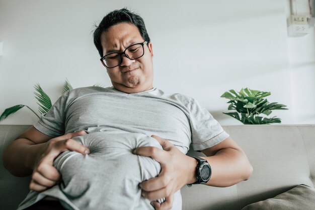 Photo fat man sitting on sofa and show obesity with stress