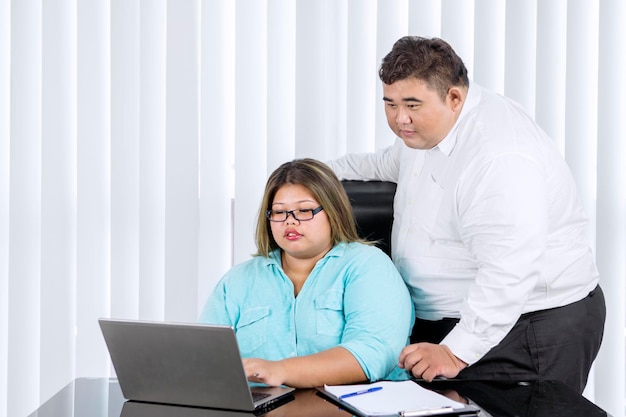 Fat man supervising her female employee working