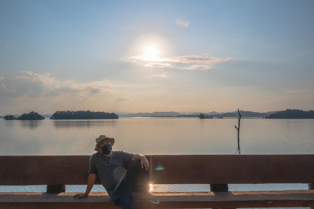 Photo fat man wearing mask with landscape view of pom pee view pointpom pee viewpoint is located in khao laem national park thong pha phum district kanchanaburi province