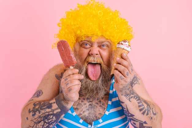 あごひげとかつらを持つ太った男はアイスキャンデーとアイスクリームを食べる