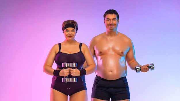 Fat man and woman in gym with dumbbells Body positive and fitness concept