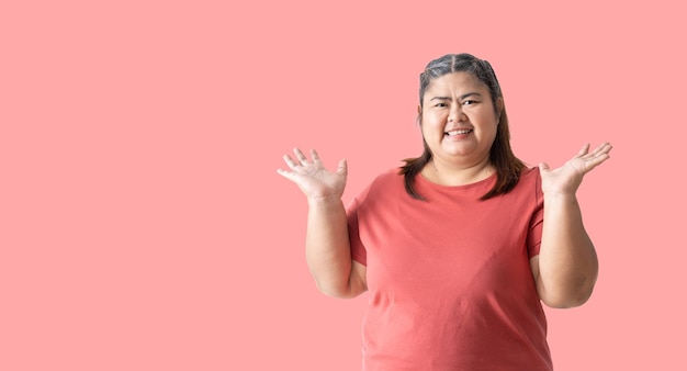 사진 뚱뚱한 여자 아시아는 분홍색 배경에 고립 된 웃는 얼굴로 위쪽에 열린 손바닥으로 양손을 보여줍니다.