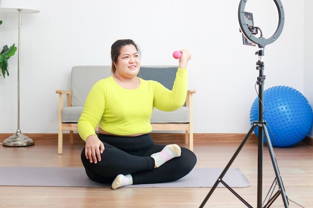 Fat woman blogger athlete in sportswear exercise in the room\
publish content online on social media platforms sports concept\
exercise and healthy health care
