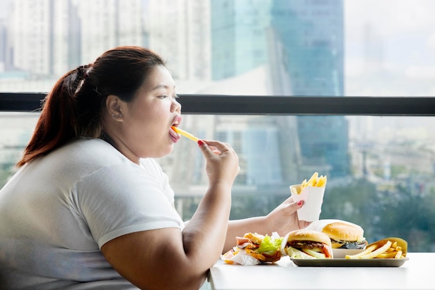 Fat woman enjoying french fries in the restaurant
