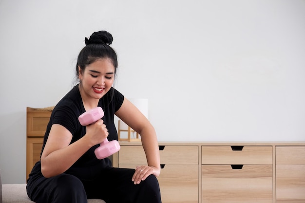 Fat woman exercising at home a beautiful oversized woman in a sports bra and casual pants sits in