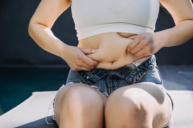 Donna grassa pancia grassa grassa donna obesa grassa donna mano che tiene il grasso della pancia eccessivo con nastro di misurazione donna dieta concetto di stile di vita