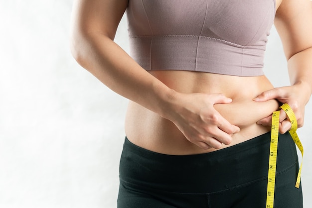 Foto donna grassa, pancia grassa, donna paffuta e obesa che tiene la mano in eccesso con il nastro di misura, concetto di stile di vita di dieta della donna