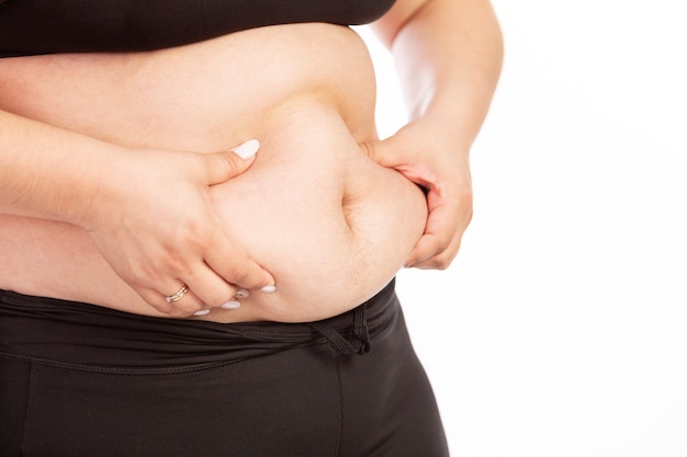 A fat woman grabs her belly with her hands, close-up