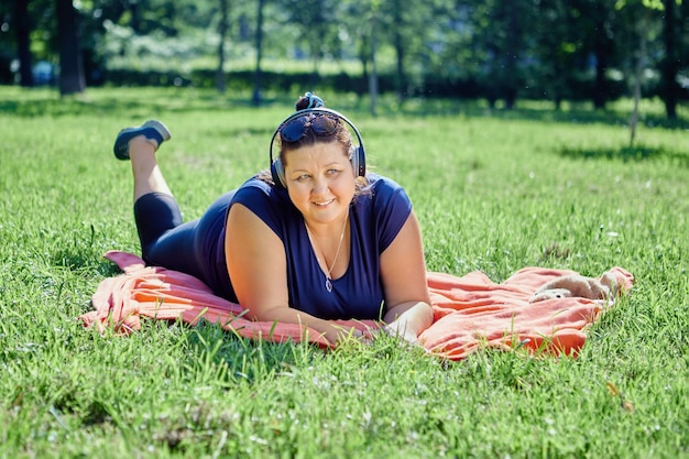 Fat woman is resting on lawn lying on her stomach