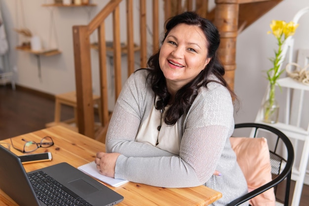 Photo a fat woman is sitting at a table with a laptop