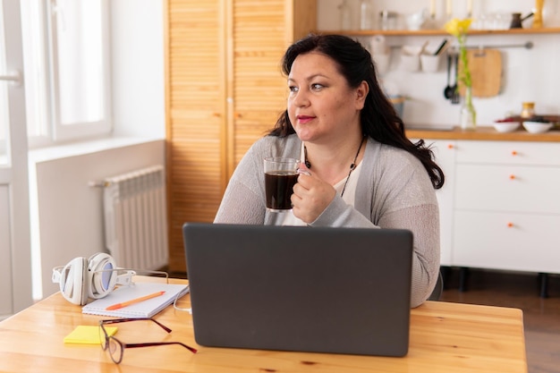 Photo a fat woman is sitting at a table with a laptop