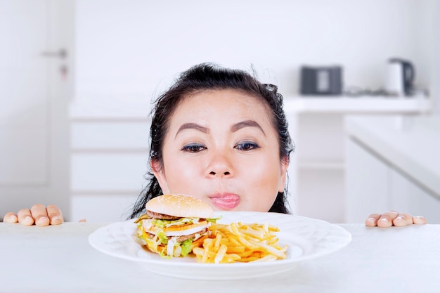 Fat woman looking at burger on a plate