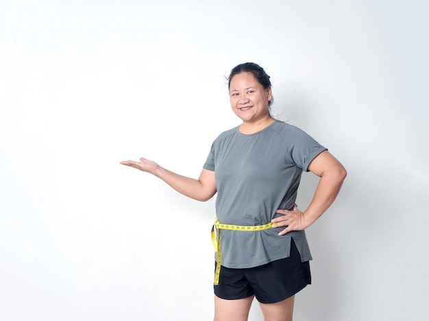 Fat woman measuring waist with tape on white background with copy space