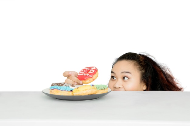 Fat woman stealing a doughnut on the table