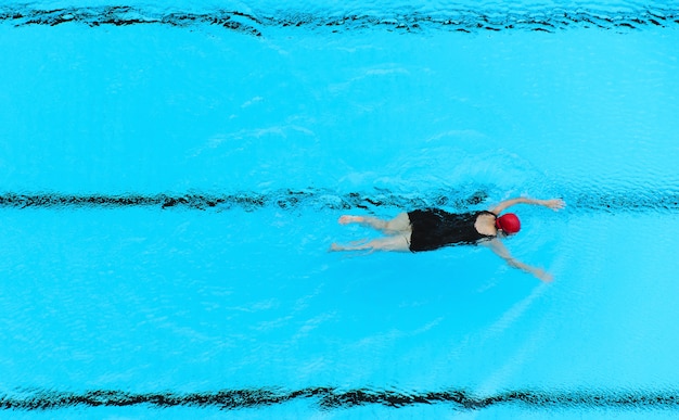 Fat woman swim at swimming pool from top view