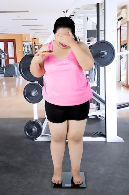 Fat woman with scales in the gym center