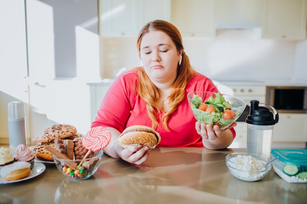 写真 座っていると食べ物を食べるキッチンで脂肪の若い女性。健康的な生活様式。