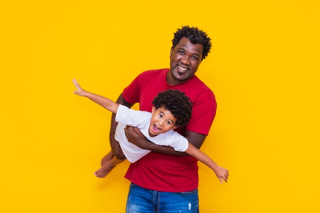 Padre e figlio afro su sfondo giallo sorridendo e giocando. concetto di festa del papà