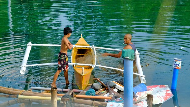 Фото Отец и сын обслуживают свою рыболовную сеть с помощью небольшой рыболовной лодки