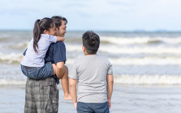 父とビーチの上を歩く2人の子供