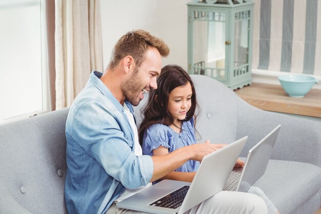 Father assisting daughter in using laptop 