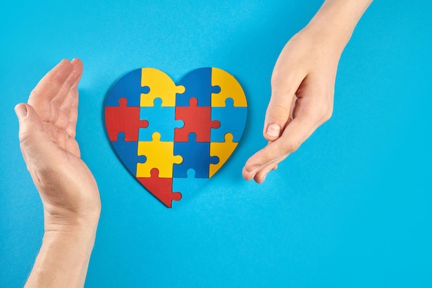 Father and autistic son hands holding jigsaw puzzle heart shape world autism awareness day