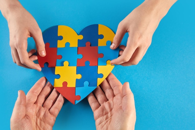 Father and autistic son hands holding jigsaw puzzle heart shape world autism awareness day