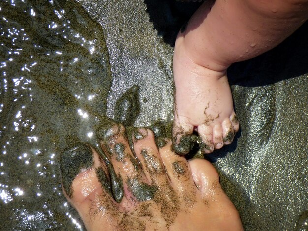 Foto padre e piedi di bambino sulla spiaggia