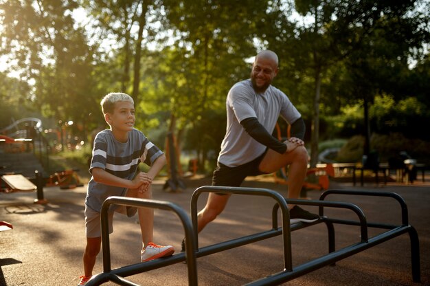 Father and boy, stretching exercise on playground