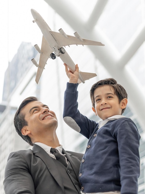 Father carries son playing aviator toy air plane imagination dreaming of being a pilot future on business district urban Dad and Son happy family concept