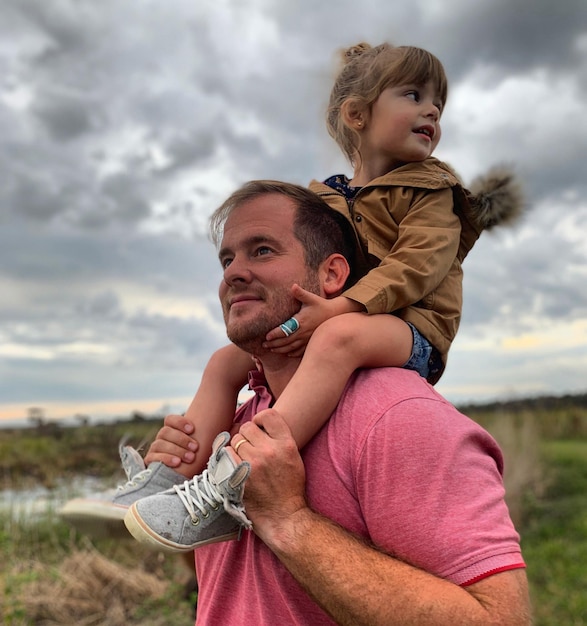 Photo father carrying daughter against sky