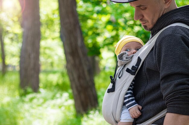 Photo father carrying his child in a baby sling