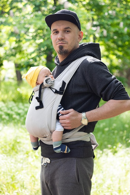 Foto padre che porta suo figlio in una fascia per bambini