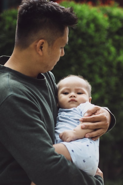 Father carrying his cute baby boy outside the house